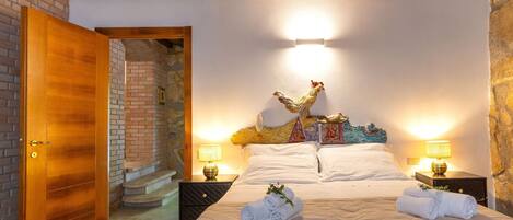 A hotel room with a bed, two bedside lamps, a wooden door, and a staircase leading to an upper level.