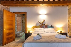 A hotel room with a bed, two bedside lamps, a wooden door, and a staircase leading to an upper level.