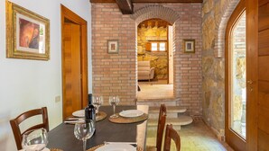 A dining area with a brick wall, wooden ceiling, and a view into a living space. - Adamo ed Eva - Holiday Rental with swimming pool on the Tuscan Coastline (Monteverdi Marittimo)
