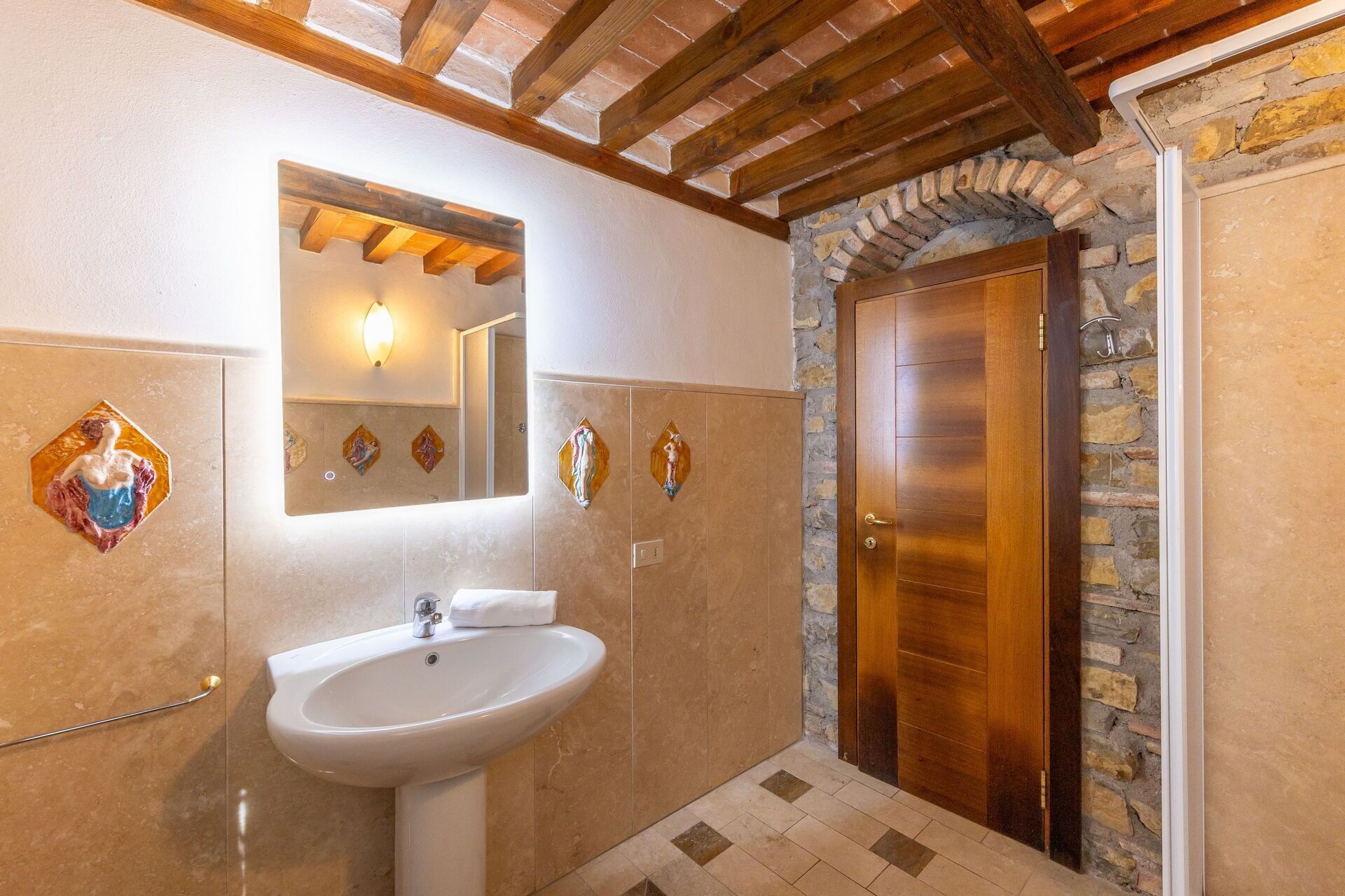 Ein Badezimmer mit Waschbecken, Spiegel und Holztür.
