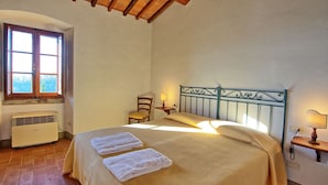 A bedroom with a bed, two bedside lamps, a chair, a window, and an air conditioner. - Le Fonti 7 - Apartment with swimming pool (Grassina)