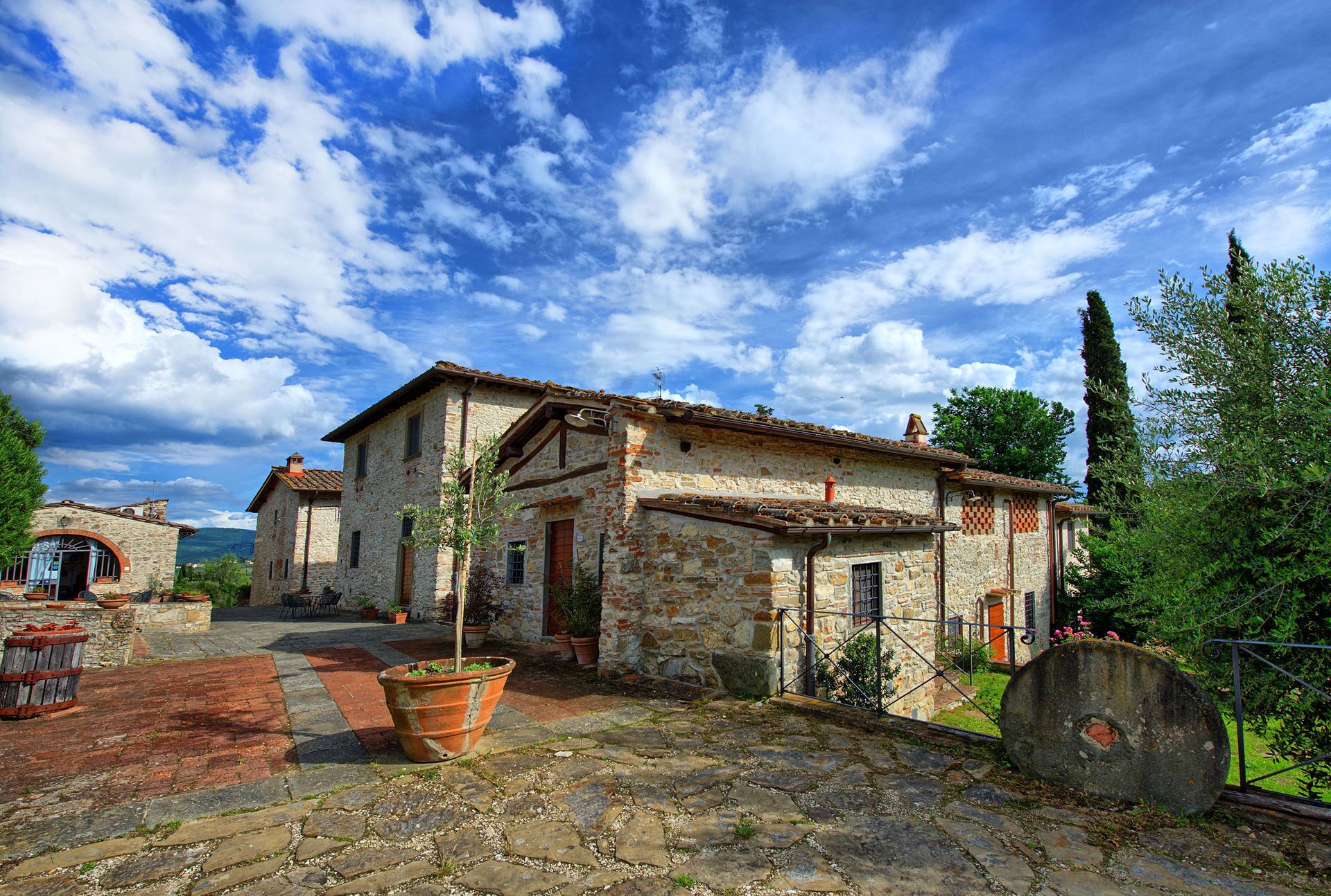 A stone building with a tiled roof, a courtyard with potted plants, and a rustic atmosphere.