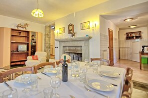 Uma sala de jantar com lareira, móveis de madeira e um pilar de pedra.