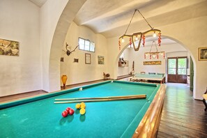 A pool table with balls, a wooden pool table, and a ceiling light fixture.