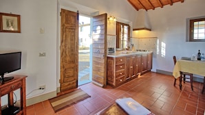 Una cocina con armarios de madera, horno empotrado y ventana con vista a un jardín.