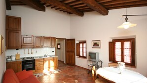 Una cocina amplia con armarios de madera, un comedor con mesa y sillas, y una ventana con cortinas.