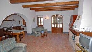 Una sala de estar con un sofá, una mesa de comedor con sillas, una chimenea y un televisor.
