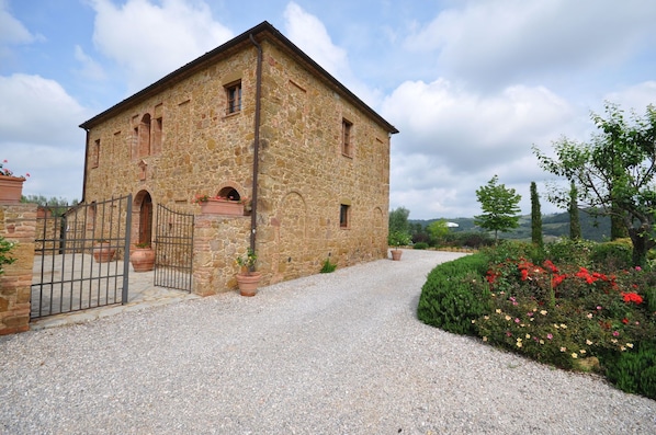 A stone building with a gravel driveway and a gated entrance.