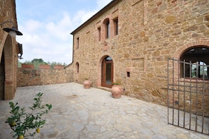 A stone building with a courtyard, a metal gate, and potted plants.
