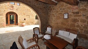 A stone-walled outdoor seating area with wooden furniture and a stone archway.
