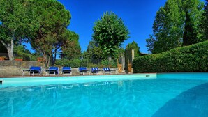 A swimming pool with blue lounge chairs and a stone wall. - Casale Ambra - Country house with private pool (Ambra)