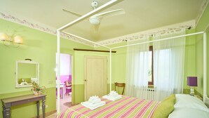 Una stanza con un letto, un comodino, uno specchio e una finestra con tende.
