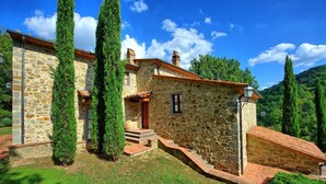 Una casa de piedra con techo de tejas rojas, un pequeño porche y una escalera que conduce a la entrada.