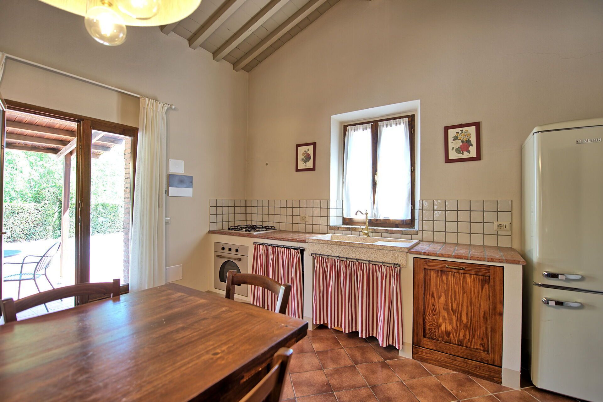 A kitchen with a wooden table, a stove, a sink, and a refrigerator.