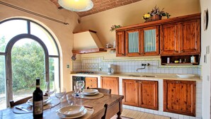 Une cuisine avec des meubles en bois, une table à manger dressée pour quatre personnes et une vue dégagée sur l’extérieur grâce à une grande fenêtre.