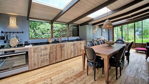 A modern kitchen with wooden cabinetry, a built-in oven, and a dining area with a wooden table and chairs.