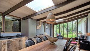 A spacious dining area with a wooden table, chairs, and a hanging light fixture.