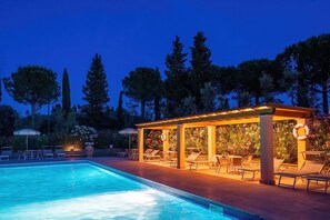 A swimming pool with lounge chairs and a covered seating area at dusk. - Montelopio 4 - Apartment with pool (Ghizzano)