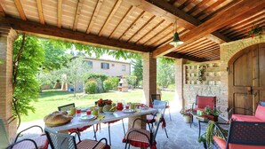 Eine Terrassensitzgelegenheit im Freien mit Esstisch, Stühlen und einer gepolsterten Bank.