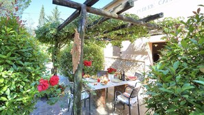 Ein Essbereich im Freien mit einer Pergola, einem Tisch für zwei Personen und Stühlen.