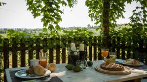 An outdoor dining table with food and drinks, surrounded by greenery and a scenic view. - Montelopio 8 - Apartment with pool (Ghizzano)