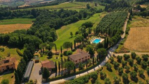 An aerial view of a rural property with a swimming pool, terraced vineyards, and traditional architecture.