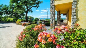 A stone building with a yellow facade, a balcony, and a garden with pink flowers. - I Gigli di Bolsena - Exclusive Villa Rental in Montefiascone, Lake Bolsena (Montefiascone)