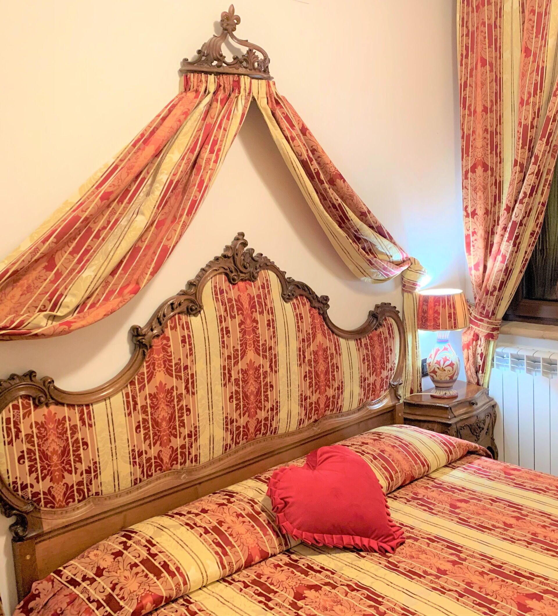 Ein Bett mit Baldachin, ein Nachttisch mit Lampe und eine Heizung.
