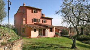 Una casa de dos pisos con techo de tejas, pared de piedra y césped.