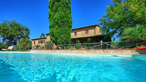 A swimming pool with clear blue water, surrounded by a stone wall and a wooden fence. - Il Frantoio - Villa with private pool (Montelupo Fiorentino)