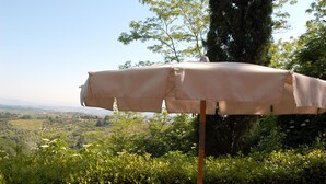 Ein Essbereich im Freien mit Tisch, Stühlen und Sonnenschirm.