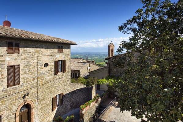 A stone building with a tiled roof, a bell tower, and a view of the countryside.