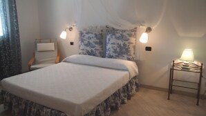 Ein Schlafzimmer mit einem Bett, einem Sessel, einem Nachttisch und einer Lampe.