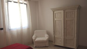 Ein Zimmer mit einem weißen Stuhl, einem roten Tisch und einer weißen Kommode.
