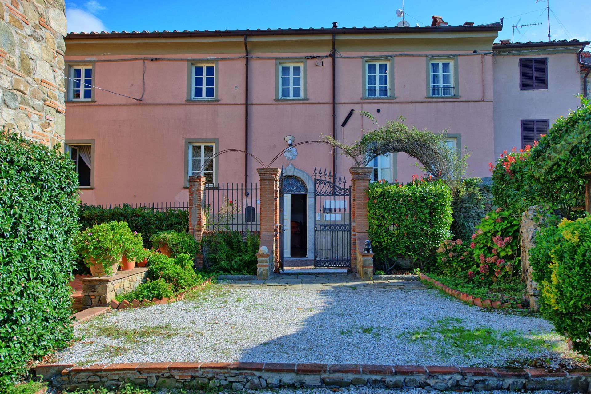 A building with a stone facade, a gated entrance, and a gravel driveway.