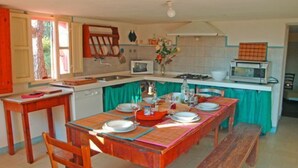 A compact kitchen with a dining table set for four, a bench, and a microwave.