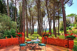 An outdoor dining area with a table and chairs, surrounded by red brick walls and potted plants. - Villa Lorenza - Villa with private pool (Palaia)