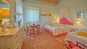 Ein Schlafzimmer mit zwei Betten, einem Holztisch, einem Stuhl, einer Kommode und einem Fenster mit Spitzenvorhängen.
