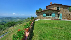 Una casa de piedra con techo de piedra, una pared de piedra y vistas al campo.