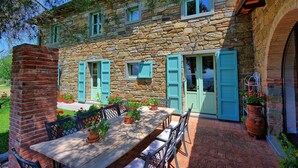 Un edificio de piedra con un patio, mobiliario exterior y vistas al mar.