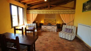 Une pièce chaleureuse avec un plafond en bois, un lit avec une literie à motifs, une chaise, une table et un radiateur.