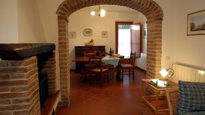 A dining area with a brick archway, wooden furniture, and a table set with plates and a bottle. - La Valle 7 - Apartment with pool (Montaione)