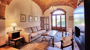 Una sala de estar acogedora con techo de ladrillo, un sofá, una mesa de centro, un televisor y una chimenea.