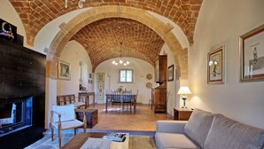 Un amplio salón con chimenea, un sofá y un comedor con mesa y sillas.