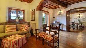 Una sala de estar acogedora con techo de madera, un sofá, un sillón y una mesa de comedor.