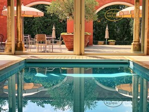 Un área de piscina exterior con cubierta de madera, sillas y sombrillas.