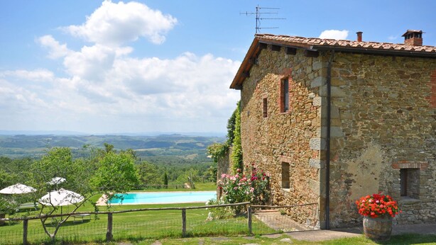 A stone building with a view of a swimming pool and landscape.