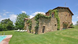 A stone building with a pool and outdoor seating.