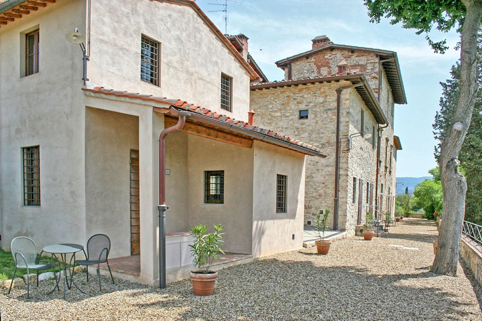 A two-story building with a patio area, outdoor seating, and potted plants.