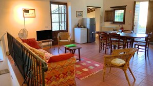 Un salon comprenant un canapé, un téléviseur et un coin repas avec des chaises et une table.
